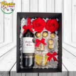 CAJA DE VINO, 2 ROSAS PRESERVADAS, 6 BOMBONES, FRUTOS SECOS, COPA Y REGALO ESPECIAL